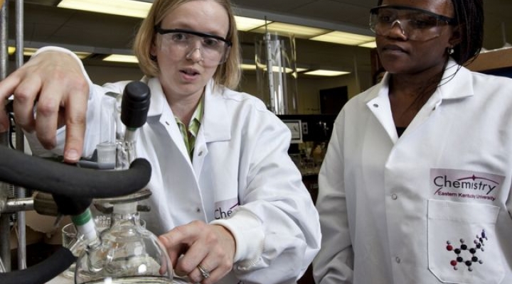 a faculty member shows a student a sample in a lab