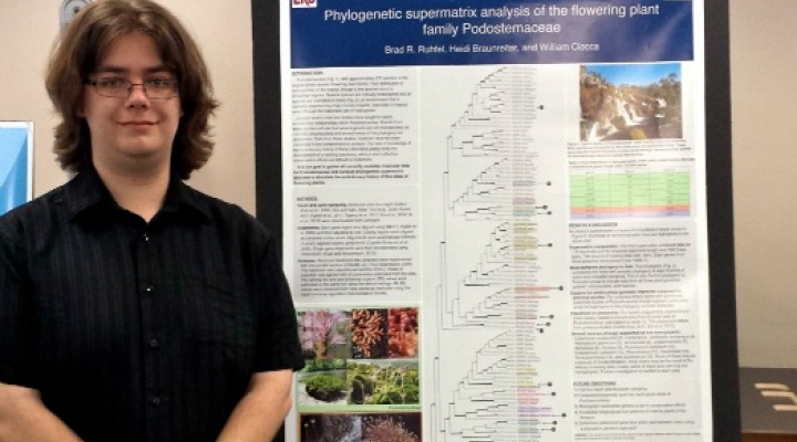 a student poses with a research poster